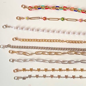 May include: A set of eight different chain styles for jewelry making. The chains are made of silver and gold metal and feature various link shapes, including round, oval, and star-shaped links.