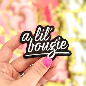 May include: A black iron-on patch with white embroidery that reads "a lil' boujie".