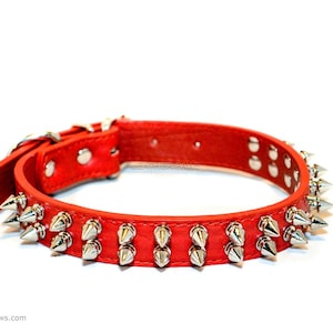 May include: Red leather dog collar with silver metal spikes. The collar is made of genuine leather and has a buckle closure. The spikes are evenly spaced around the collar and are about 1 inch long. The collar is available in a variety of sizes.