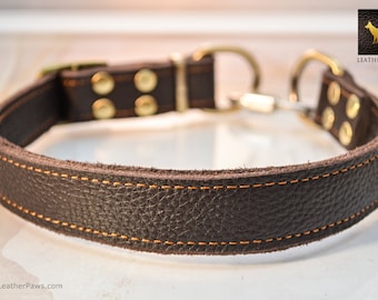 May include: A brown leather dog collar with a brass buckle and two brass D-rings. The collar is stitched with orange thread and has a "LEATHER PAWS" logo on the buckle.