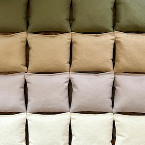 May include: A set of 12 bean bags in four different colors: green, beige, light purple, and white. The bean bags are arranged in a grid pattern.