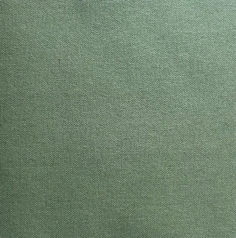 May include: Close-up of a solid olive green fabric with a textured weave. The material has a consistent color and a subtle, slightly rough surface. The fabric appears to be a medium weight, suitable for various textile projects.