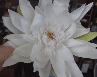 Puede incluir: Una gran flor artificial blanca con un centro amarillo. La flor tiene muchos pétalos y está dispuesta en forma circular.