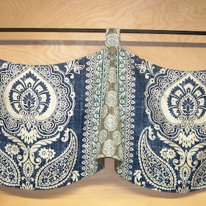 May include: A blue and white patterned valance with a paisley design. The valance is hung on a black curtain rod.