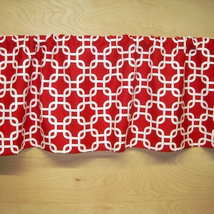 May include: Red and white valance with a geometric pattern. The valance is made of fabric and has a ruffled edge.