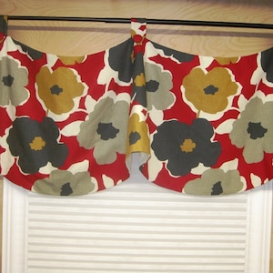 May include: A red, gray, and gold floral valance with a scalloped edge. The valance is hung on a black curtain rod.