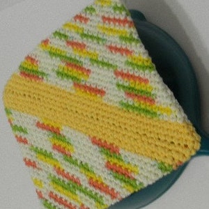 Puede incluir: Un agarrador de olla tejido a crochet en forma triangular con un patrón amarillo, verde, naranja y blanco. El agarrador de olla tiene una franja amarilla en el medio.