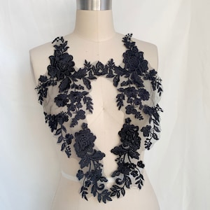 May include: Black floral lace applique with a delicate design. The lace is made of a sheer fabric with intricate floral patterns. This applique is perfect for adding a touch of elegance to any project.