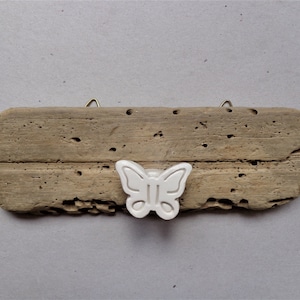 May include: A rustic wooden sign with a white ceramic butterfly knob. The sign is weathered and has a natural wood grain.
