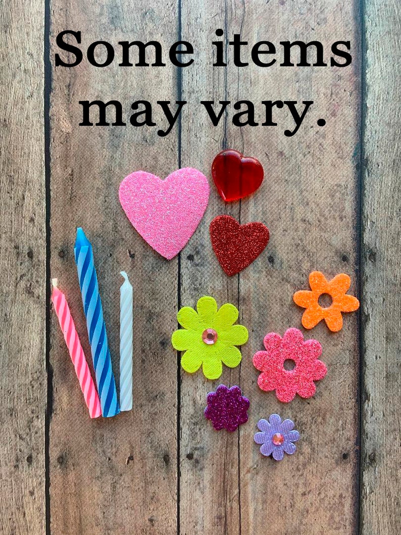 May include: Assortment of decorative items including glittery hearts, colorful flower shapes, and striped candles. The text "Some items may vary" is displayed at the top of the image. The items are arranged on a wooden background.