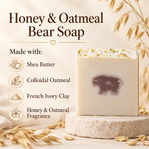 May include: A rectangular off-white bar of soap featuring a brown bear silhouette in the center and gold flecks on top. The text reads Honey & Oatmeal Bear Soap, Made with: Shea Butter, Colloidal Oatmeal, French Ivory Clay, Honey & Oatmeal Fragrance.