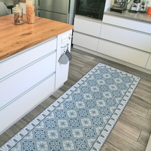 May include: A blue and white patterned kitchen rug with a geometric design. The rug is placed on a wood floor in a kitchen.