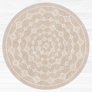 May include: A round beige rug with a white geometric pattern. The pattern is made up of repeating squares and diamonds.