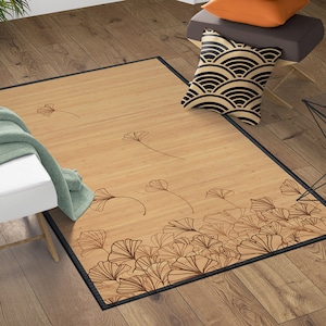 May include: A rectangular bamboo rug with a black border. The rug features a light brown background with a pattern of stylized ginkgo leaves in a darker brown color. The leaves are scattered across the rug.