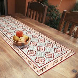 Pode incluir: Um corredor de mesa com um design geométrico em vermelho, branco e cinza. O corredor está sobre uma mesa de madeira com uma tigela de frutas em cima.