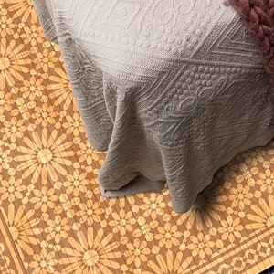 May include: A brown and beige patterned rug with a floral design. The rug has a border with a geometric pattern. The rug is partially covered by a beige blanket with a textured pattern.