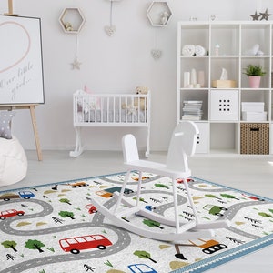 May include: A white rocking horse on a play mat with a road and cars design. The mat is blue, gray, and white with green trees and yellow accents. The mat is in a nursery with a white crib and a white beanbag chair.