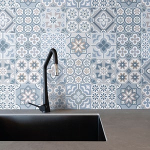 May include: A black kitchen faucet with a single handle is mounted above a black sink. The backsplash behind the sink is tiled with a pattern of blue and brown geometric shapes.