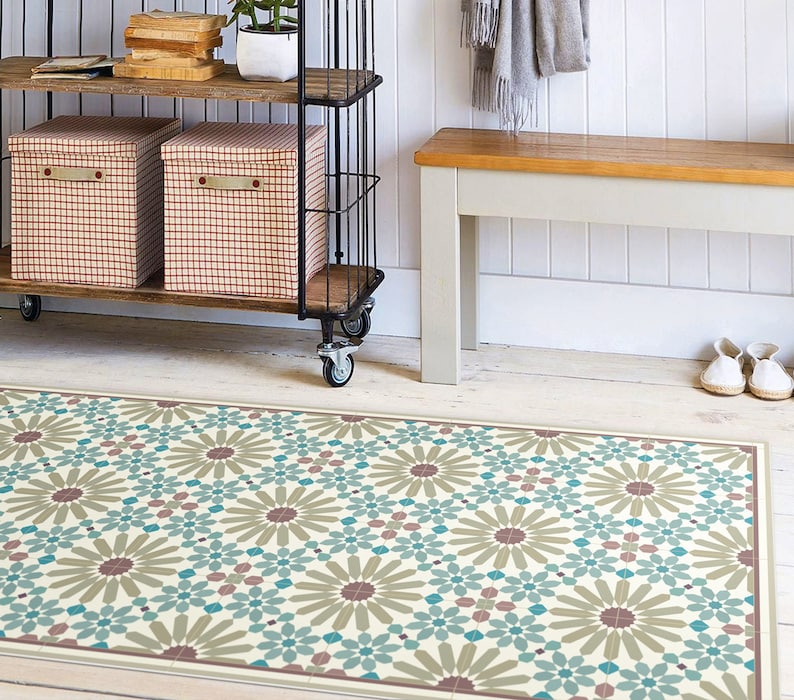Op de afbeelding: Een gepatroneerd tapijt met een bloemmotief in tinten blauw, groen en bruin. Het tapijt ligt voor een houten bank en een metalen rek.