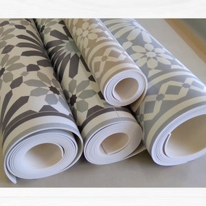 May include: Three rolls of patterned vinyl flooring with a geometric design. The flooring is in shades of gray, white, and beige.
