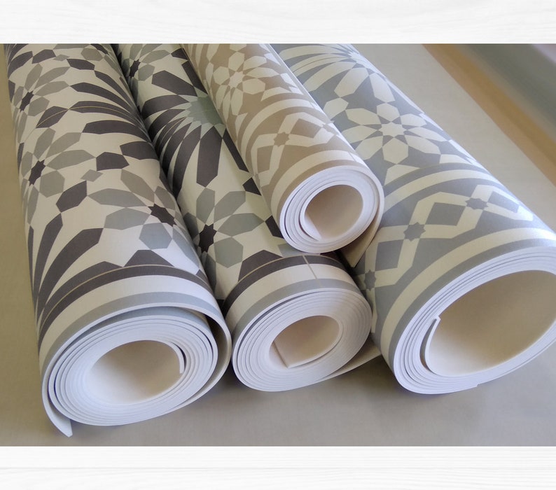 May include: Three rolls of patterned vinyl flooring with a geometric design. The flooring is in shades of gray, white, and beige.