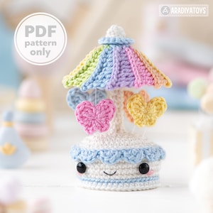 May include: A crocheted carousel with a rainbow-colored canopy and four butterfly-shaped hanging ornaments. The carousel has a smiling face and black button eyes.