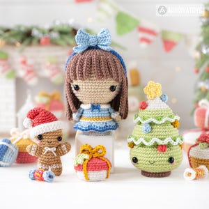 Op de afbeelding: Een verzameling handgemaakte gehaakte kerstversieringen. Bevat een pop met een blauwe strik, een peperkoekmannetje met een kerstmuts, een groene kerstboom en een ingepakt cadeau. De ornamenten zijn kleurrijk en hebben vriendelijke gezichten.