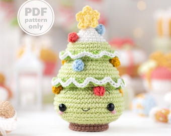 May include: A crocheted Christmas tree with a smiling face, adorned with colorful ornaments and a yellow star. The tree is green with white and brown accents. The text "PDF pattern only" is in a white circle.