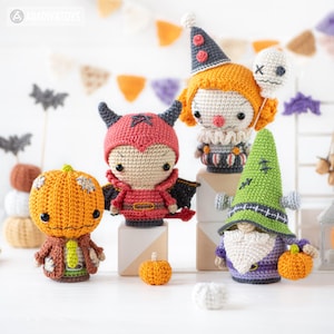 May include: A collection of four crocheted dolls featuring a pumpkin-headed figure, a red devil with wings, a clown with a white balloon, and a green-hatted gnome. Each doll is crafted with detailed yarn textures, vibrant colors, and small accessories.
