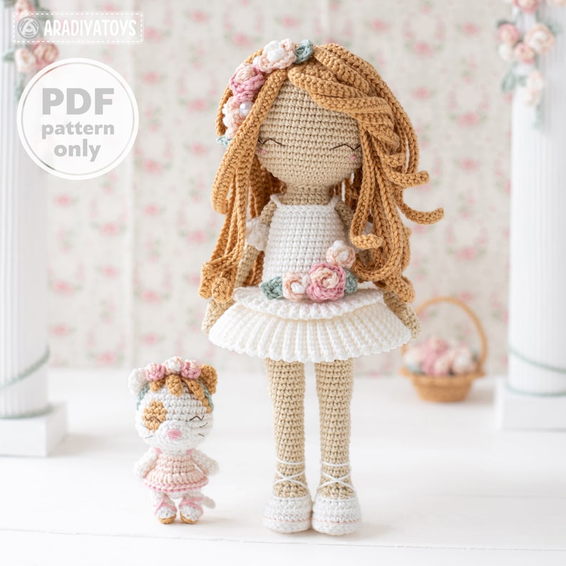 May include: A crocheted doll with long, flowing, light brown hair and a white dress adorned with pink and green floral accents. A smaller crocheted cat doll is also present. The image includes the text "PDF pattern only".