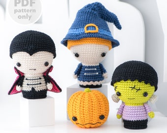 May include: A set of four crocheted Halloween characters: a witch with a blue hat, a vampire with a red cape, a Frankenstein monster with green skin, and a pumpkin. The characters are all small and have big eyes. The characters are sitting on a white surface.