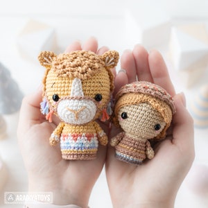 May include: Two crocheted amigurumi toys, a brown and yellow horse and a brown girl with a brown and orange hat, are held in the palms of a person's hands.