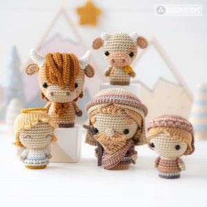 May include: A set of five crocheted amigurumi toys, including a cow, a bull, a shepherd, a shepherdess, and an angel. The toys are all in a neutral colour palette of brown, beige, and white.