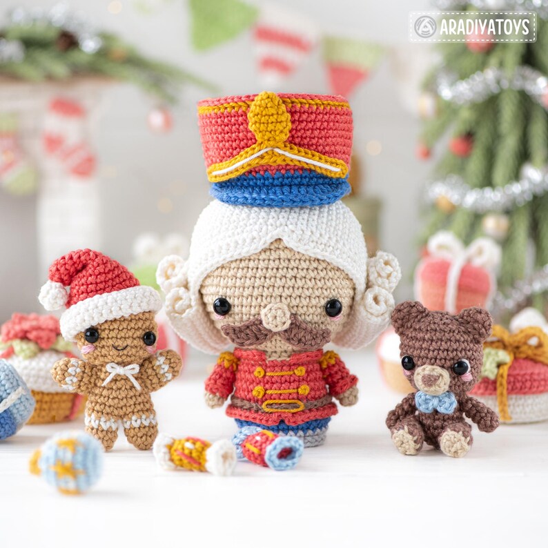 Op de afbeelding: Een verzameling handgemaakte gehaakte kerstversieringen. De set bevat een notenkraker, een peperkoekmannetje en een teddybeer, allemaal met gedetailleerde kenmerken en feestelijke kleuren. De ornamenten worden gepresenteerd met vakantiedecoraties op de achtergrond.