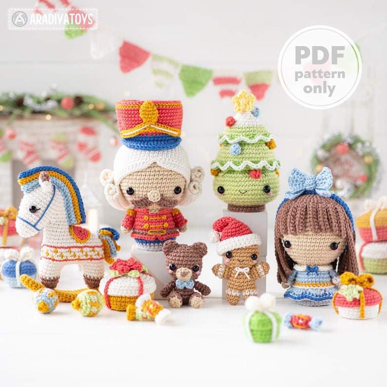 Op de afbeelding: Een verzameling handgemaakte gehaakte kerstversieringen, waaronder een notenkraker, paard, kerstboom, teddybeer en pop. De ornamenten zijn in verschillende kleuren, met details zoals een rood en goud uniform en een blauwe strik.