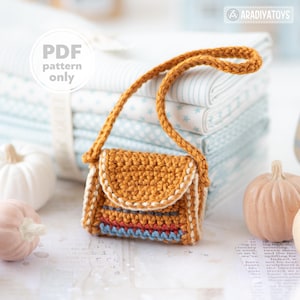 Può includere: Una piccola borsa all'uncinetto arancione, con patta e tracolla lunga. La borsa presenta una striscia decorativa rossa, blu e bianca. Il testo "PDF pattern only" è visibile nell'immagine.