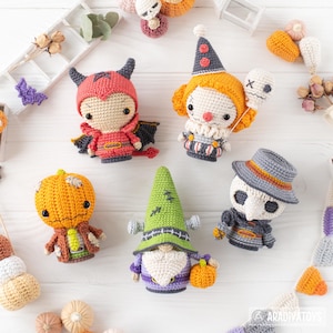 May include: A collection of five crocheted dolls featuring a red devil, a clown with a balloon, a pumpkin-headed figure, a green-hatted gnome, and a plague doctor. Each doll is crafted with intricate yarn details and distinct character features.