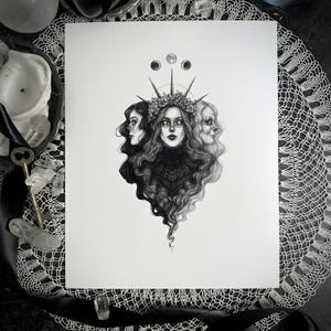 May include: Black and white art print featuring a central female figure with three faces, adorned with a floral crown and moon symbols. The detailed illustration showcases flowing hair and intricate patterns, evoking a mystical theme.