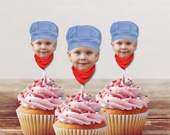 May include: Three pink cupcakes with colorful sprinkles topped with blue and white striped engineer hats and red bandanas. The hats have a child's face printed on them.