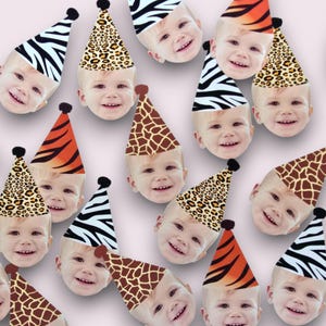 May include: A collection of smiling baby faces wearing party hats with animal print designs, including zebra stripes, leopard spots, giraffe patterns, and tiger stripes. The hats have a black pom-pom on top, set against a soft pink background.