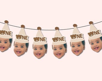 Könnte beinhalten: Ein dekoratives Banner mit sechs wiederkehrenden Ausschnitten eines Babygesichts, das einen beigefarbenen Partyhut trägt. Jeder Hut ist mit einem braunen Bommel versehen und zeigt ein braunes Bärensymbol neben dem Wort ONE in fetten, braunen Großbuchstaben.