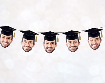 May include: A graduation banner with five black graduation caps with gold tassels. Each cap has a face of a person wearing a graduation cap underneath.