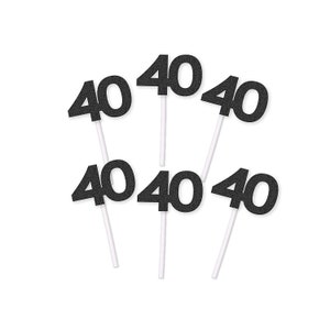 May include: Six black glitter cupcake toppers with the number "40" on each. The toppers are on white sticks.