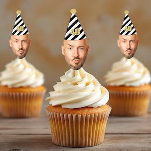 May include: Three cupcakes with white frosting and black and white striped party hats with gold glitter "40" on them. Each cupcake has a face printed on the hat.