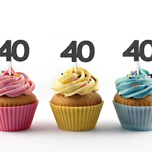 May include: Three cupcakes with black glitter '40' toppers. The cupcakes are frosted in pink, yellow, and blue.