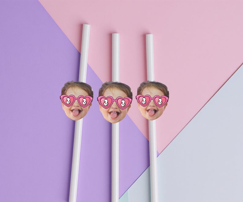 May include: Three white straws with attached images of a child's face wearing heart-shaped sunglasses with the number 3. The background is a geometric design of pink, purple, and white.