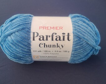 May include: A ball of Premier Parfait Chunky yarn in a light blue color. The label reads "Premier Parfait Chunky" with details about the yarn's weight and material. The yarn is 100% polyester.