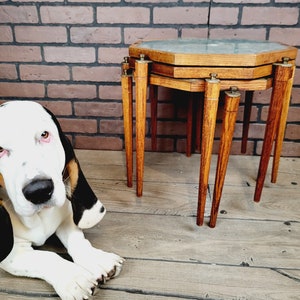 May include: A set of three nesting tables with a wood frame and a green marble top. The tables are stacked on top of each other and have a unique octagonal shape.