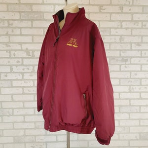 May include: A maroon zip-up jacket with a gold embroidered logo that says "EVENT STAFF" and the letters "M" and "M".
