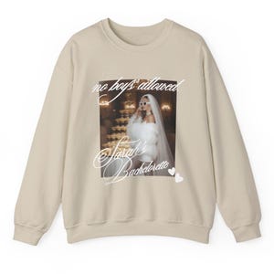 May include: Beige sweatshirt with a graphic featuring a bride in sunglasses and the text "no boys allowed" and "Sarah's Bachelorette". Two small white hearts are at the bottom right.